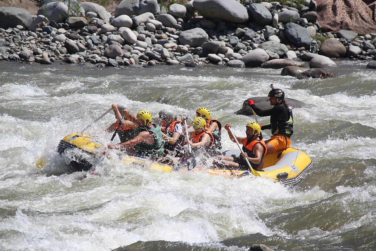 Guests and a guide paddling a raft through whitewater rapids