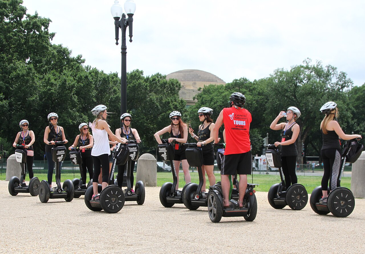 A helmeted Segway tour group listening to their guide